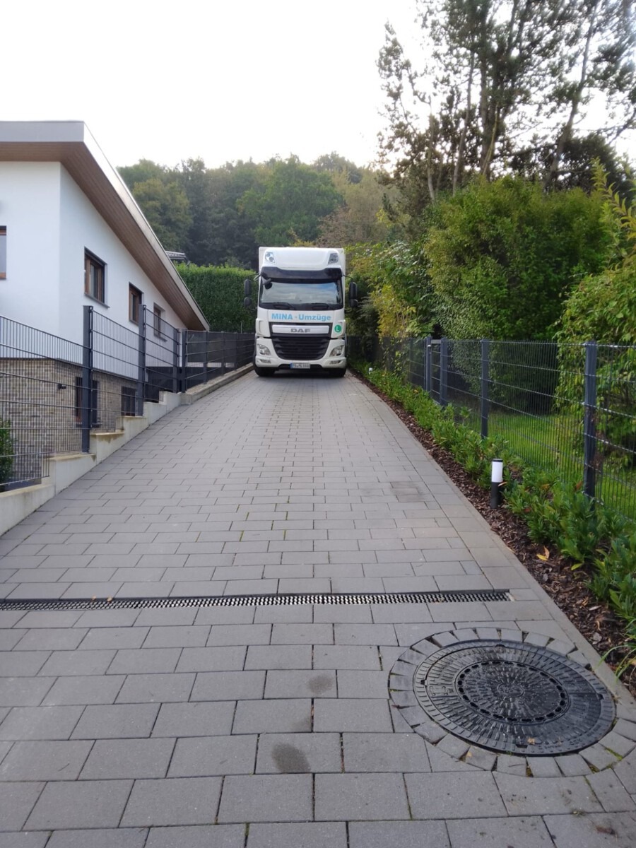 MINA-Umzüge-LKW fährt die steile, schmale Einfahrt eines Hauses in Hanglage in Bad Driburg hinauf